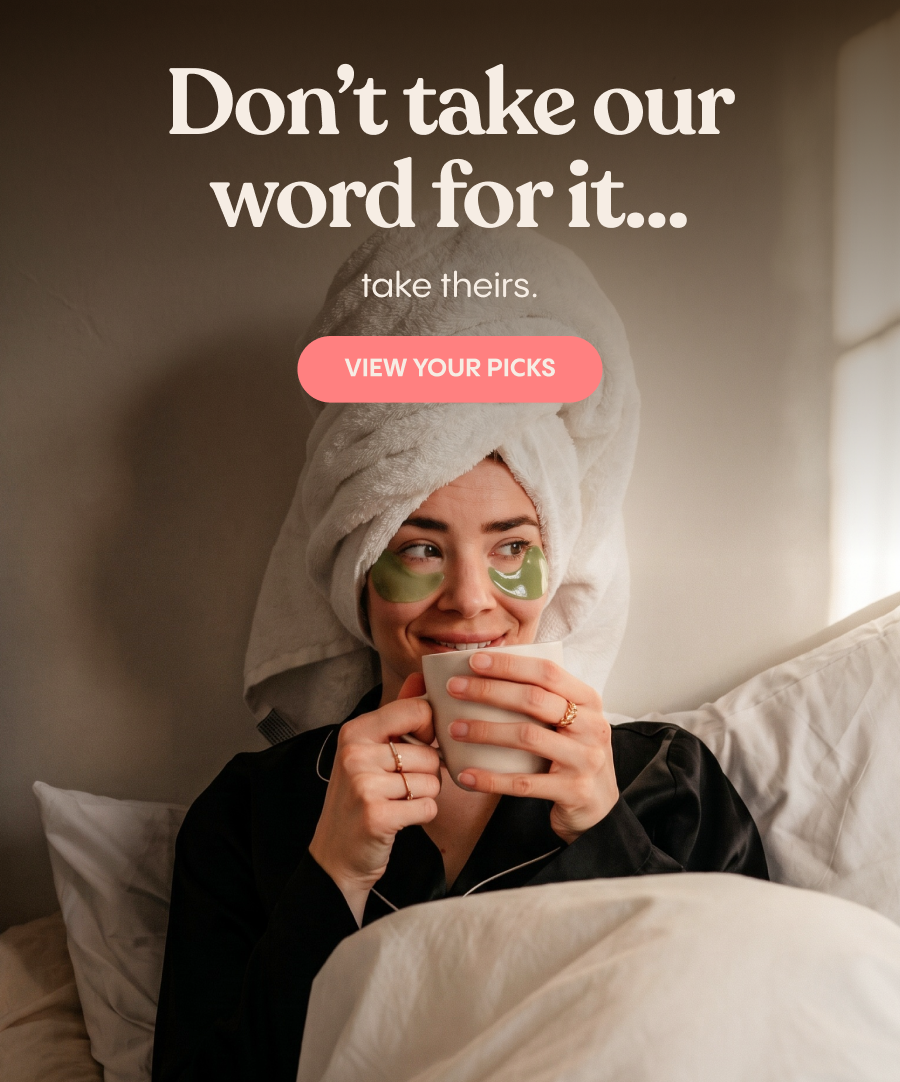 A warm, softly lit portrait shows a person with a white towel wrapped around their head, green under-eye patches, and black clothing, holding a white ...